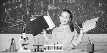 Documenting the result of experiments. Little child at laboratory. Little girl learn chemistry in...