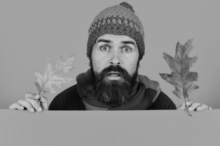 Guy with surprised face wears warm hat on orange backgroundの写真素材