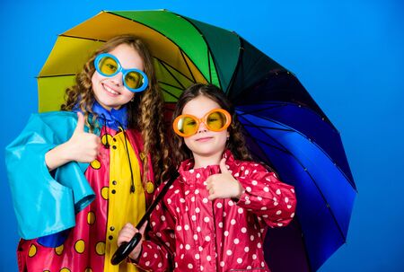 cheerful hipster children, sisterhood. rain protection. Rainbow. happy small girls with colorful umbrella. family bonds. Small girls in raincoat. autumn fashion. Autumn snugglesの写真素材