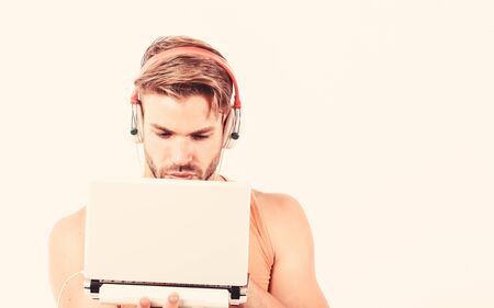 Searching for favorite music. muscular man listen audio. man in earphones isolated on white. e book. unshaven man listening audio book. usinf laptop and headset. copy spaceの写真素材