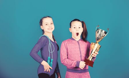 Deserved award. Sport achievement. Girls athletic kids celebrate victory. Athletic girls with golden goblet. Win championship. Our team first place. Children gymnasts athletic kids happy championsの写真素材