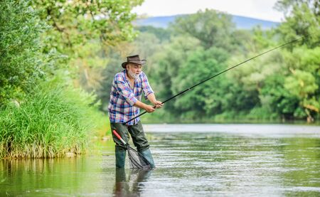 Mature man fishing. Male leisure. Fisherman with fishing rod. Senior man catching fish. Activity and hobby. Fishing freshwater lake pond river. Happiness is rod in your hand. Retired fishermanの写真素材