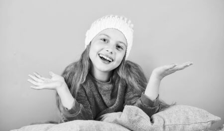 Kid dreamy lean on pillows. Winter season coziness attribute. Winter season concept. Winter fashion accessory. Kid girl knitted hat. Winter accessory concept. Girl long hair dream pink backgroundの写真素材