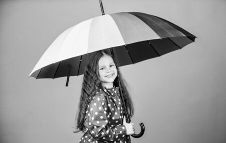 cheerful hipster child in positive mood. rain protection. Rainbow. happy little girl with colorful umbrella. little girl in raincoat. autumn fashion. Happiness highlights her beautyの写真素材