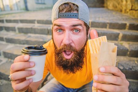 Urban lifestyle nutrition. Junk food. Carefree hipster eat junk food while sit stairs. Snack for...