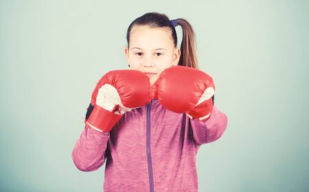 With great power comes great responsibility. Contrary to stereotype. Boxer child in boxing gloves. Female boxer. Sport upbringing. Boxing provide strict discipline. Girl cute boxer on blue backgroundの写真素材