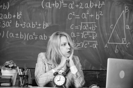 teacher with alarm clock. Time. Back to school. Teachers day. Study and education. Modern school. Knowledge day. School. Home schooling. Tired woman. woman in classroom. What time is it nowの写真素材