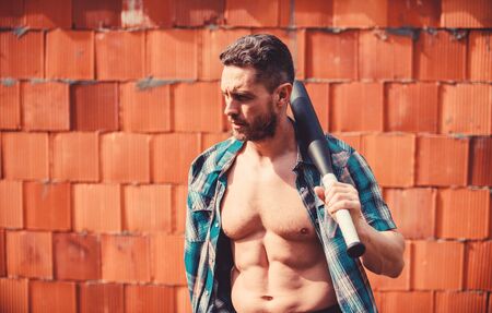 Feel my strength. Man unshaven face muscular torso hold black baseball bat. Strong temper. Principle concept. Confident his strength. Bully guy carry cudgel brick wall background. Power and strengthの写真素材