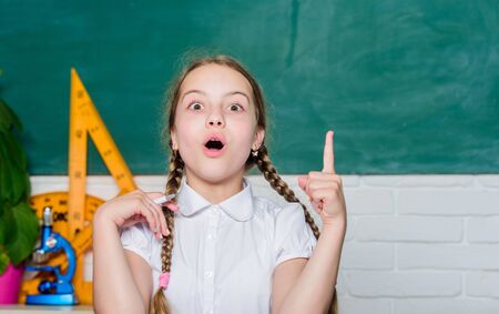 Girl cute child sit school classroom chalkboard background. Small kid study school. Knowledge day. Hometask concept. Back to school on first of september. Hooked on learning. Accelerating into futureの写真素材