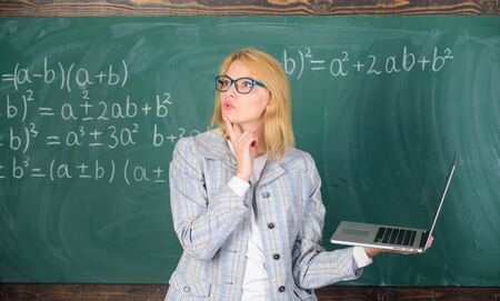 Educator smart clever lady with modern laptop searching information chalkboard background. Online schooling concept. Educational site for teachers. Woman wear eyeglasses holds laptop surfing internetの写真素材