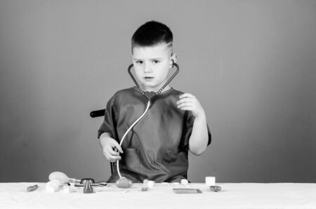 Kid little doctor sit table with stethoscope and medical tools. Medicine concept. Health care. Medical examination. Medical education. Play game. Boy cute child future doctor career. Healthy lifeの写真素材