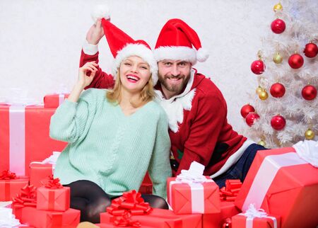 Christmas gift concept. Couple wear hats as santa claus christmas tree background. Couple in love enjoy christmas celebration. It is easy to spread happiness around. Happy family celebrate christmasの写真素材