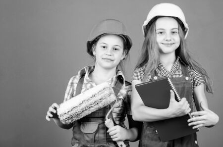 Foreman inspector. Repair. small girls repairing together in workshop. Labor day. 1 may. engineering idea. Little kids in helmet with tablet and roller. Repair shop. Repair work with childrenの写真素材