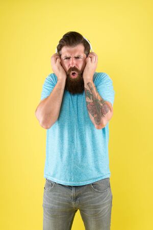Bearded guy dislike music. Irritating sound. Man listening music wireless headphones. Equalizer settings. Awful sound. Hipster listen broken headphones music gadget. Hateful song. Music tasteの写真素材