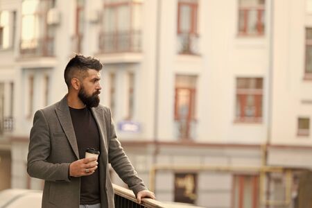 Beginning of busy day. Hipster with paper cup walking in city. Businessman in hipster style holding takeaway coffee. Bearded man enjoying morning coffee. Drinking his cup first thing in the morningの写真素材