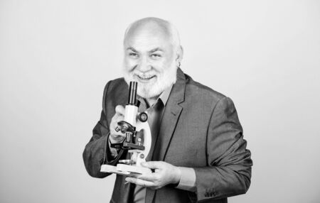 Mature man formal suit with microscope.