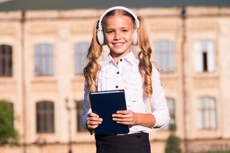 Girl cute schoolgirl hold book and headphones.の写真素材