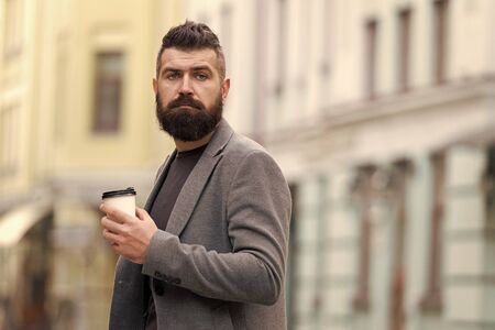 One more sip of coffee. City lifestyle. Businessman well groomed appearance enjoy coffee break out of business center urban background. Relax and recharge. Man bearded hipster drink coffee paper cupの写真素材