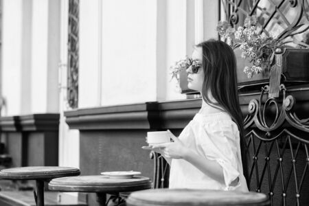 Woman in sunglasses drink coffee outdoors. Girl relax in cafe cappuccino cup. Caffeine dose. Coffee for energetic successful day. Breakfast time in cafe. Girl enjoy morning coffee. Waiting for dateの写真素材
