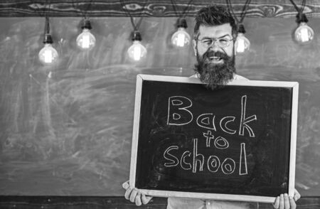 Man with beard and mustache on happy face welcomes colleagues, chalkboard on background. Teacher in...