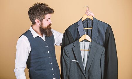 Being a tailor. Mens tailor. Hipster holding tailor made coats at department store. Bearded man...