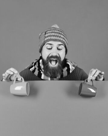 Man in warm hat holds brown cups on green background,の写真素材