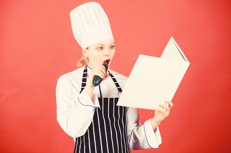 woman in cook hat and apron eat cucumber. professional chef in kitchen. Cuisine. Housewife with...