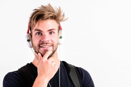 Download music application. Modern people concept. Man tousled hairstyle wear plastic earphones gadget. Enjoy music everywhere you go. Youth music taste. Student handsome guy listening musicの写真素材