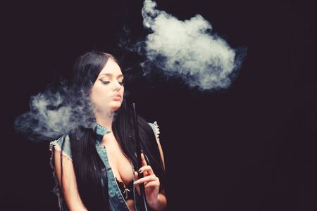 Attractive busty brunette smoking vaping device. Girl vaping. Hookah bar. Electronic cigarette....