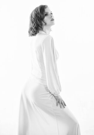 Vintage fashion concept. Woman elegant lady with retro hairstyle and makeup posing in white dress. Sexy vintage fashionable dress. Outfit for party. Girl attractive vintage model on white backgroundの写真素材