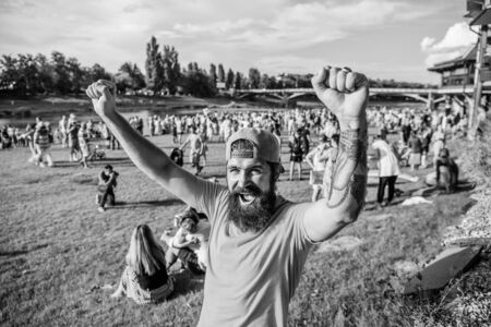 Fan zone. Entertainment concept. Visit summer festival. Summer fest. Hipster in cap happy celebrate event fest or festival. Man bearded hipster in front of crowd. Open air concert. Music festivalの写真素材