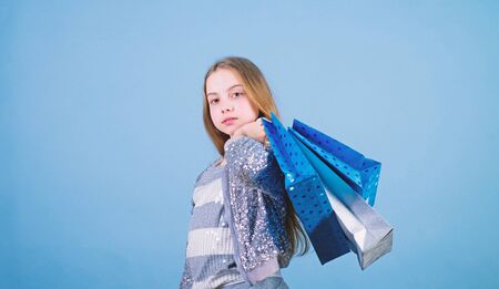 Fashion girl customer. Happy child in shop with bags. Shopping day happiness. Birthday girl shopping. Fashion boutique. Fashion trend. Fashion shop. Little girl with bunch packages. Seasonal saleの写真素材