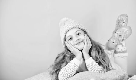 Kid girl wear cute knitted fashionable hat and scarf accessory. Winter accessory concept. Girl long hair dream pink background. Kid dreamy face wear knitted accessory. Winter fashion accessoryの写真素材