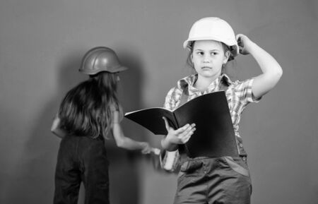 small girls repairing together in workshop. Labor day. 1 may. engineering idea. Future career. Little kids in helmet with tablet and roller. Foreman inspector. Repair. choosing a career. best careerの写真素材