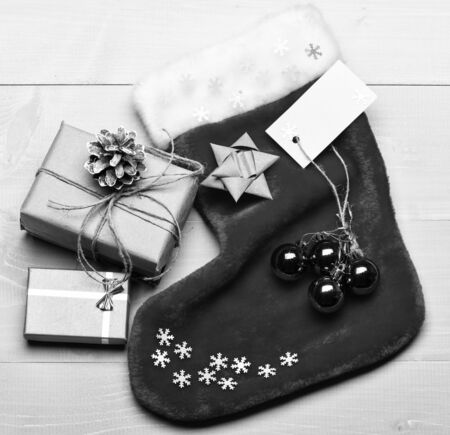 Attributes of christmas. Santa stocking with christmas gift box. Christmas decorative sock light background top view. Christmas stocking sock shaped bag fill with presents. Keep family traditions.の写真素材