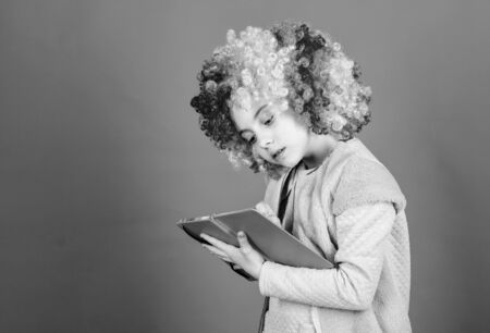 Time to have fun. Circus school. Study hard. Ridiculous story. Reading funny book. Literature club. Jokes book concept. Kid colorful curly wig artificial hair clown style hold book. Reading jokesの写真素材