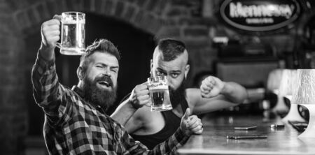 Friends relaxing in pub with beer. Refreshing beer concept. Men drinking beer together. Hipster brutal man drinking beer with friend at bar counter. Men drunk relaxing having fun. Alcohol drinksの写真素材