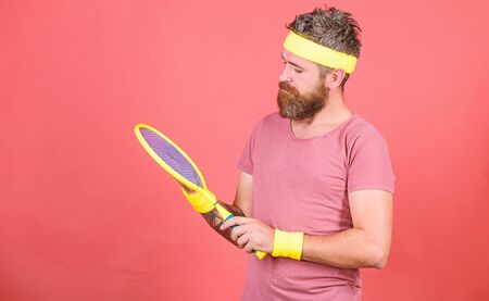 Tennis player retro fashion. Tennis sport and entertainment. Athlete hipster hold tennis racket in hand red background. Play tennis for fun. Man bearded hipster wear sport outfit. Reach top againの写真素材