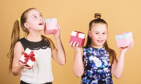 Kids girls delighted gift. Girls adorable celebrate birthday. Kids happy loves birthday gifts. Shopping and holidays. Sisters enjoy presents. Children hold gift boxes beige background. Oh happy dayの写真素材