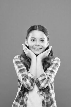 Real joy. smiling school girl. worker uniform. kid long hair. small girl checkered shirt. happy child. happy childrens day. childhood happiness. little girl orange background. kid fashionの写真素材