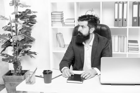 Usual day in office. Man bearded hipster boss sit in leather armchair office interior. Boss at workplace. Manager formal clothing corporate style working. Business people concept. Busy boss in officeの写真素材