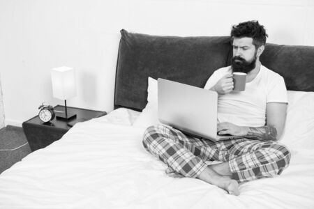 Sleeping at working place. asleep and awake. energy and tiredness. businessman with computer. bearded man hipster work on laptop. brutal sleepy man in bedroom. mature male drink coffeeの写真素材
