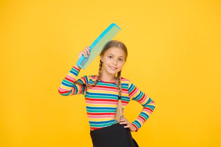 Haircare begins with combing. Little child hold hair comb yellow background. Haircare and combing....