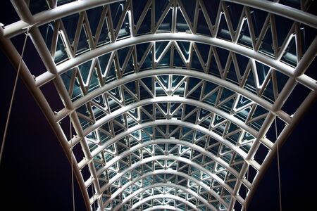Architectural element of bridge dark night sky background. Steel glass construction illuminated many...