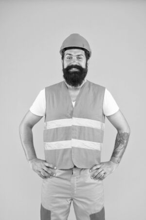 Building tomorrow. Bearded man smiling in protective workwear for building activity. Happy building renovation contructor on yellow background. Building and construction industryの写真素材