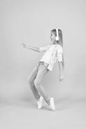 The tunes turning her mood around. Happy small girl dancing to music. Dancing girl. Small girl listening to music in headphones. Cute child enjoying happy dance music. Music is happiness for herの写真素材