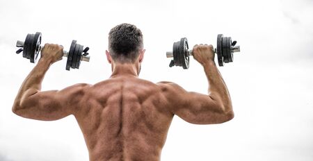 Muscular man exercising with dumbbell rear view. Pain is temporary, pride is forever. Sportsman with strong back and arms. Sport equipment. Bodybuilding sport. Sport lifestyle. Dumbbell exercise gym.の写真素材