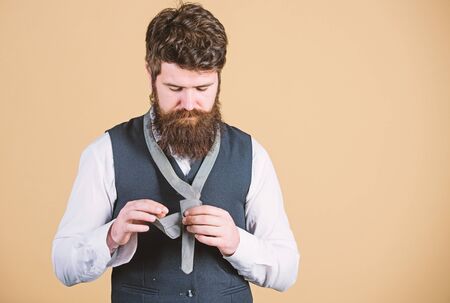 Looking classy. Elegant man. Bearded man tying a tie. Brutal caucasian man adjusting fashion accessory. Man with long beard and moustache dressing in classic style, copy spaceの写真素材