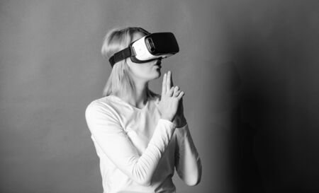 Young woman using a virtual reality headset. Woman using VR device. Person with virtual reality helmet isolated on blue background. Network VR.の写真素材