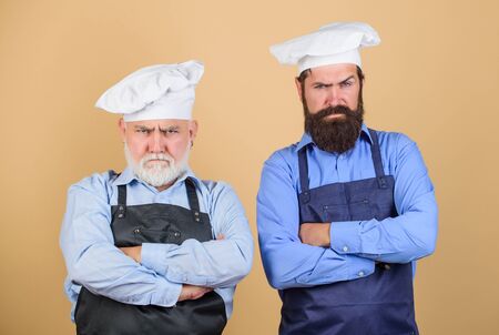 who is the best. family dinner. father and son cooking. commercial kitchen at restaurant. professional chefs. serious men in cook hat. mature bearded chef. tired of cooking. masters of kitchenの写真素材